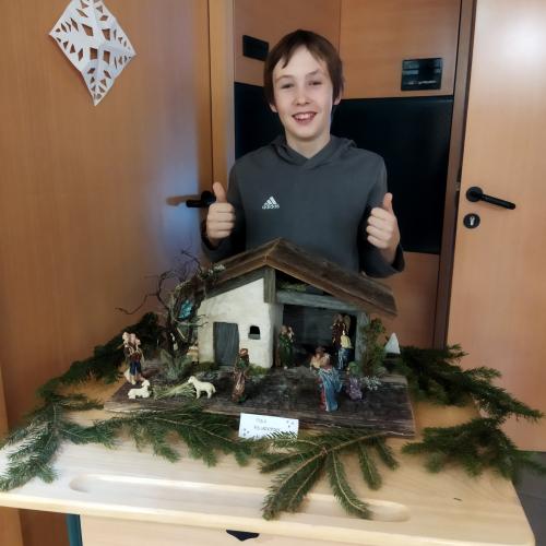 Ein Schüler präsentiert seine Weihnachtskrippe