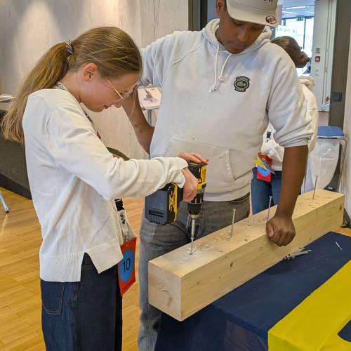 Eine Schülerin schraubt eine Schraube ins Holz