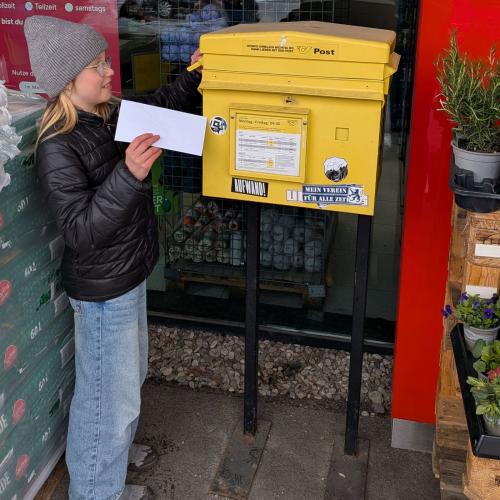 Eine Schülerin wirft einen Brief in den Postkasten