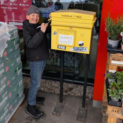 Ein Schüler wirft einen Brief in den Postkasten