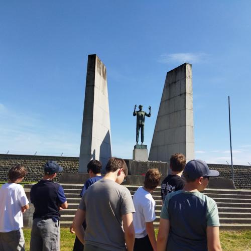 Schüler:innengruppe vor einem Mahnmal in Mauthausen