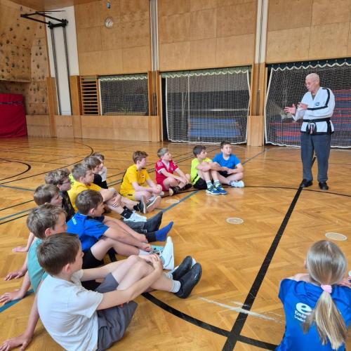Schülerinnen und Schüler in der Turnhalle sitzend