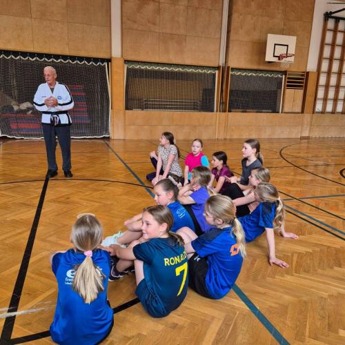 Schülerinnen und Schüler in der Turnhalle sitzend