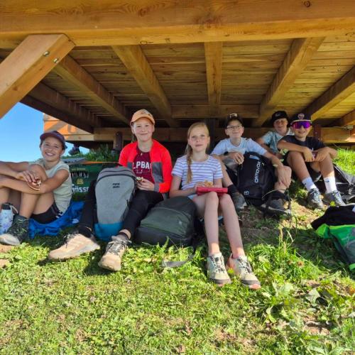 Kinder suchen Schatten unter einem Holzverbau